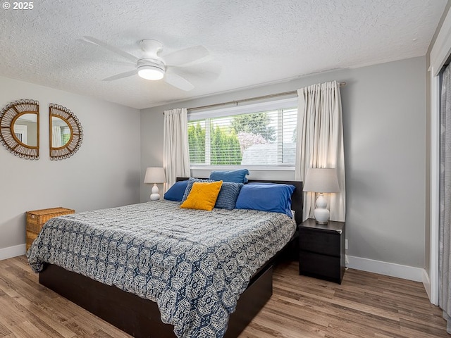 bedroom with baseboards, wood finished floors, and a textured ceiling