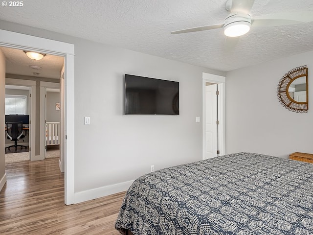 bedroom featuring baseboards, a ceiling fan, a textured ceiling, and light wood finished floors