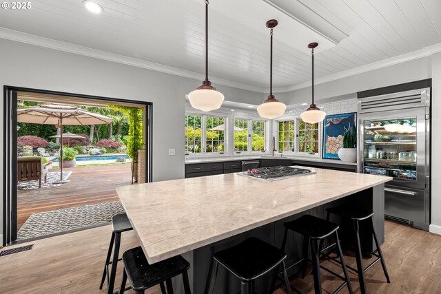21424 SW 65th Ave, Tualatin, OR 97062 - kitchen with appliances with stainless steel finishes, light wood finished floors, a center island, a kitchen bar, and light stone counters