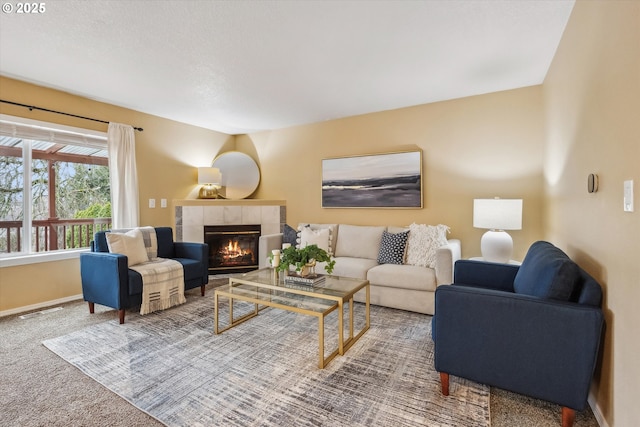 living area featuring visible vents, baseboards, carpet, and a tile fireplace