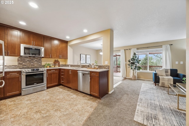 kitchen with tasteful backsplash, recessed lighting, brown cabinets, appliances with stainless steel finishes, and a sink