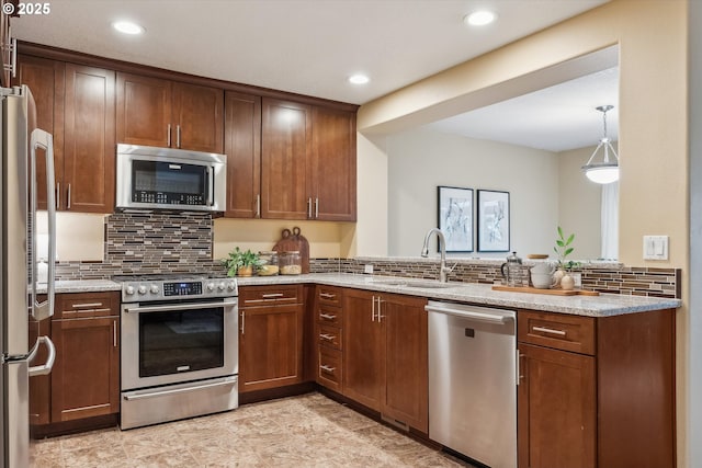 kitchen with backsplash, light stone countertops, stainless steel appliances, and a sink