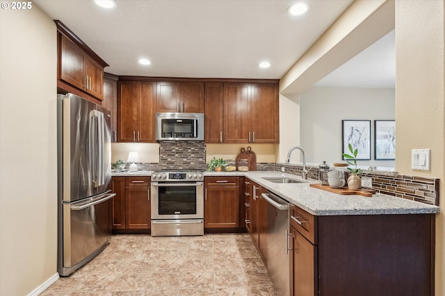 kitchen featuring light stone countertops, recessed lighting, a sink, stainless steel appliances, and backsplash