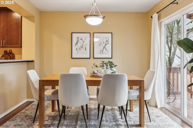 dining area featuring baseboards and light wood-style flooring