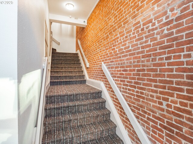 interior space with multiple windows, brick wall, stainless steel fridge, and light hardwood / wood-style floors