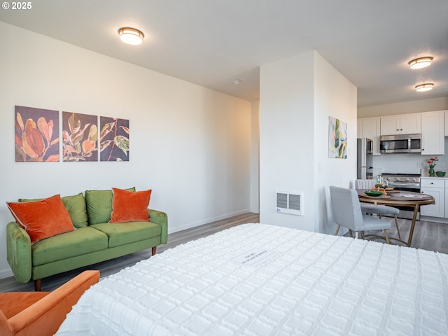 bedroom with dark hardwood / wood-style floors and stainless steel refrigerator