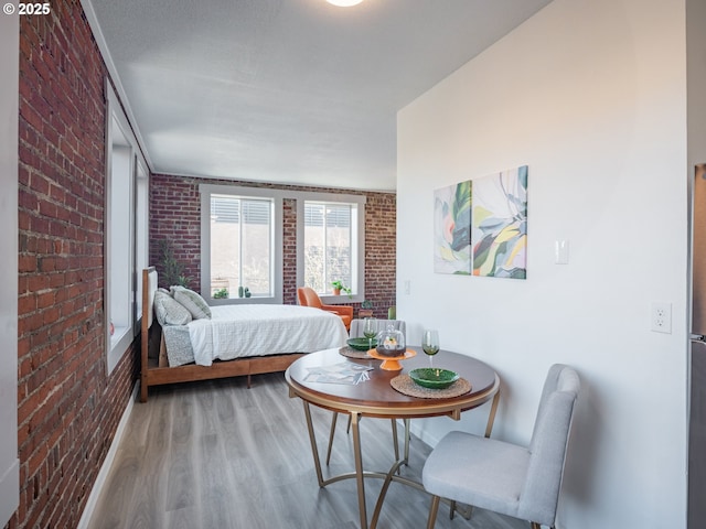 bedroom with hardwood / wood-style flooring and brick wall