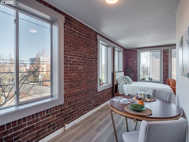 bedroom with light hardwood / wood-style floors and brick wall