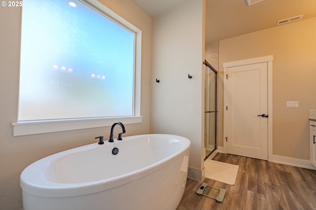 10107 NE 136th Ave, Vancouver, WA 98682 - full bath with wood finished floors, a soaking tub, a shower stall, vanity, and baseboards