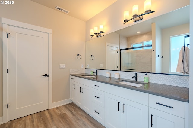 10107 NE 136th Ave, Vancouver, WA 98682 - full bathroom with wood finished floors, a shower stall, double vanity, backsplash, and baseboards
