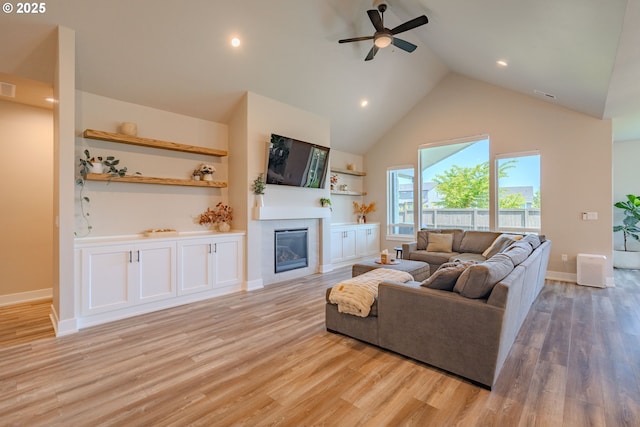 10107 NE 136th Ave, Vancouver, WA 98682 - living area with high vaulted ceiling, a glass covered fireplace, a ceiling fan, light wood finished floors, and baseboards