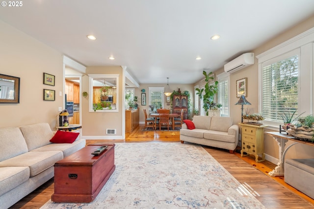 living room with light wood finished floors, a wall mounted air conditioner, visible vents, and recessed lighting