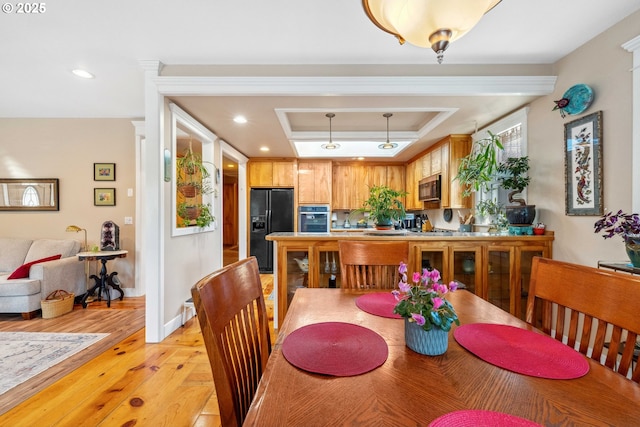 dining area with recessed lighting, light wood finished floors, baseboards, and a raised ceiling