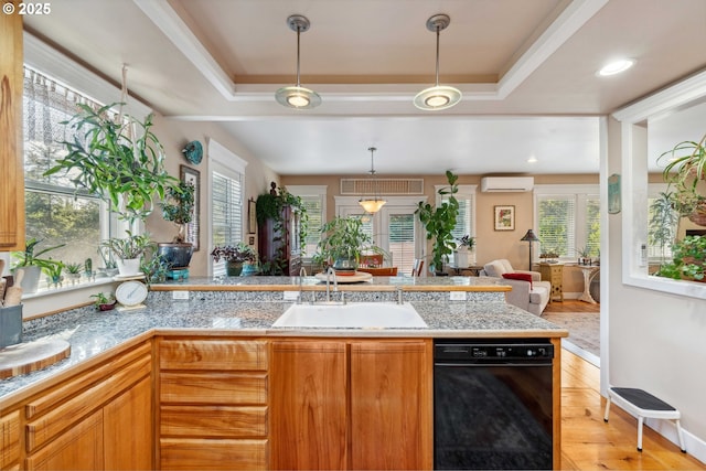 kitchen featuring a sink, hanging light fixtures, a raised ceiling, and a wall unit AC