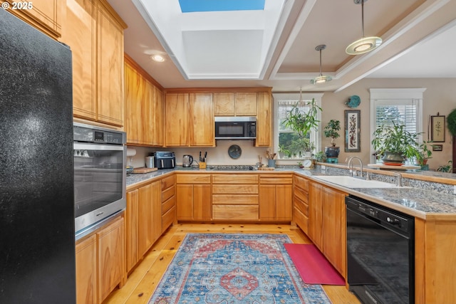 kitchen with light wood-style floors, a sink, a peninsula, and black appliances