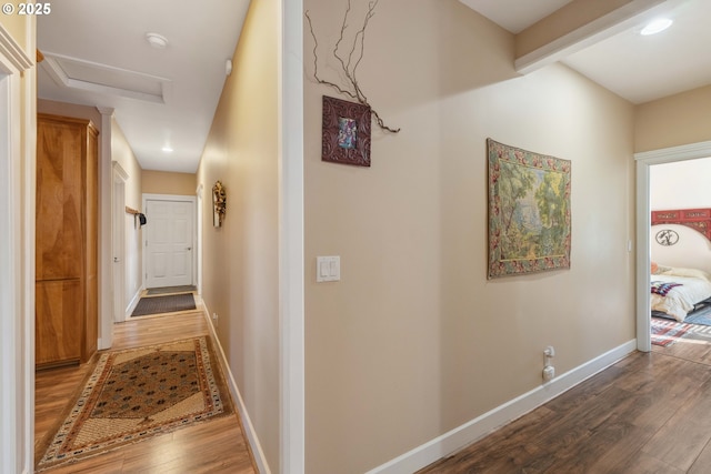 corridor with baseboards, recessed lighting, attic access, and wood finished floors