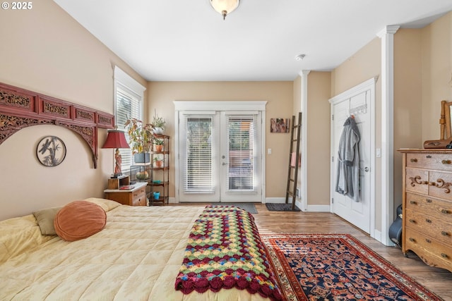 bedroom featuring french doors, access to outside, wood finished floors, and baseboards