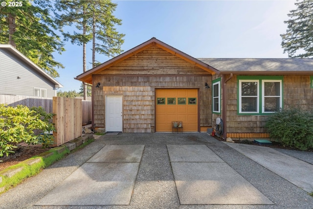 view of front of house featuring concrete driveway, fence, and a garage
