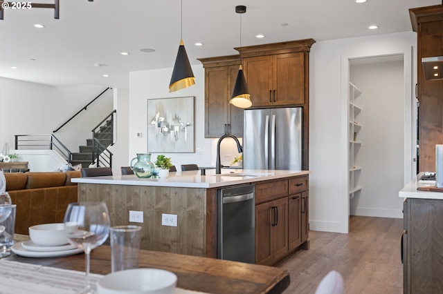 kitchen featuring stainless steel appliances, an island with sink, light wood-type flooring, and recessed lighting