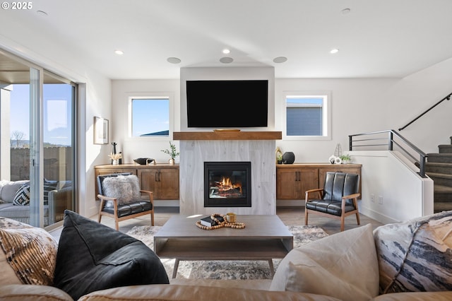 living area featuring recessed lighting, wood finished floors, a fireplace, and stairs