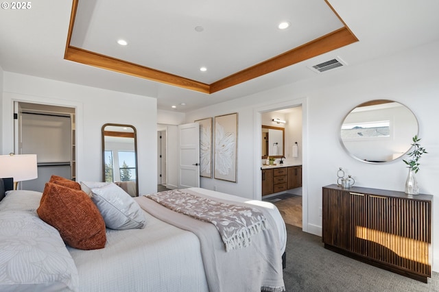 bedroom featuring a walk in closet, recessed lighting, a raised ceiling, visible vents, and dark carpet