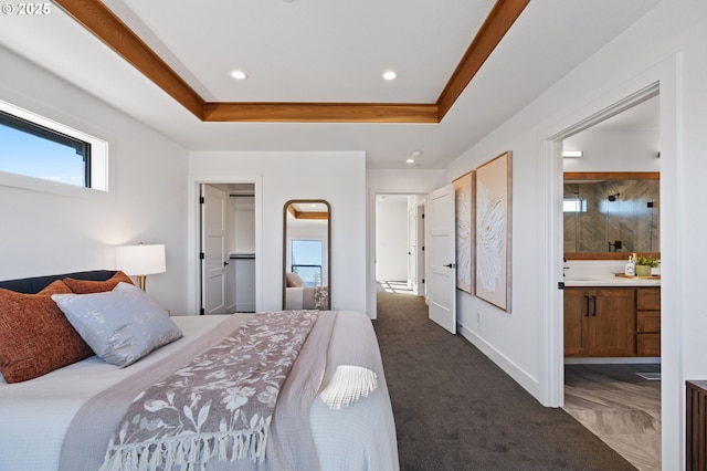 bedroom featuring recessed lighting, baseboards, a raised ceiling, dark carpet, and ensuite bath