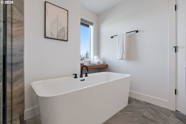 full bathroom featuring a freestanding tub and baseboards