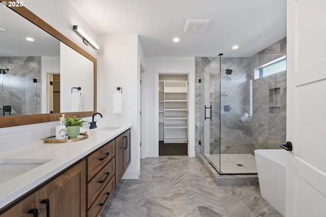 full bath with recessed lighting, a sink, a spacious closet, a shower stall, and double vanity