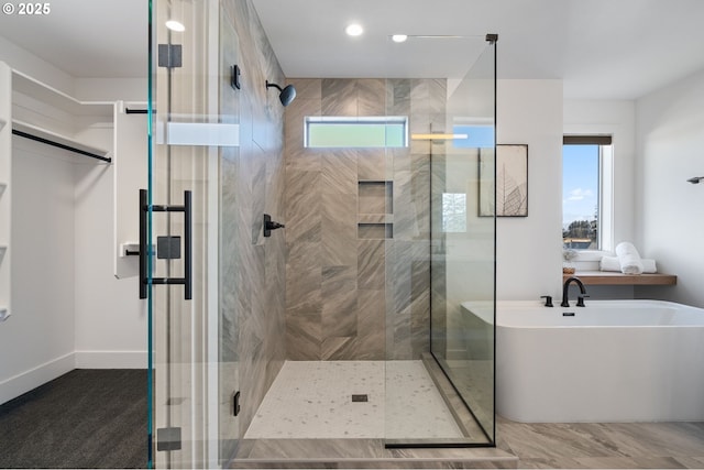 full bathroom featuring a stall shower, a soaking tub, and baseboards