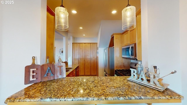 kitchen featuring stone countertops, kitchen peninsula, stainless steel appliances, and hanging light fixtures