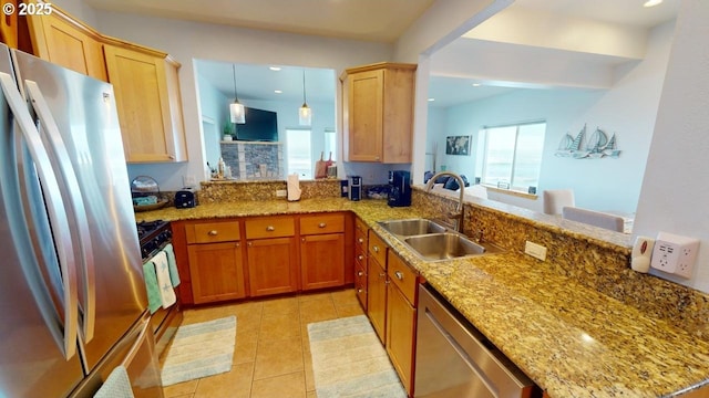 kitchen with sink, hanging light fixtures, stainless steel appliances, light stone counters, and kitchen peninsula