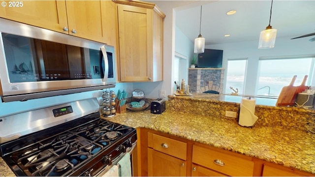 kitchen with light stone countertops, appliances with stainless steel finishes, light brown cabinets, a stone fireplace, and hanging light fixtures