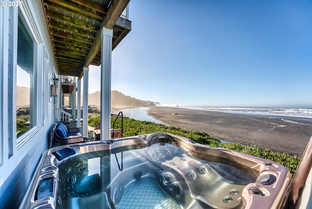 balcony featuring a water view and a hot tub