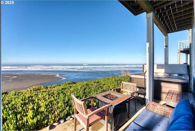 balcony featuring a water view, a beach view, and an outdoor living space with a fire pit