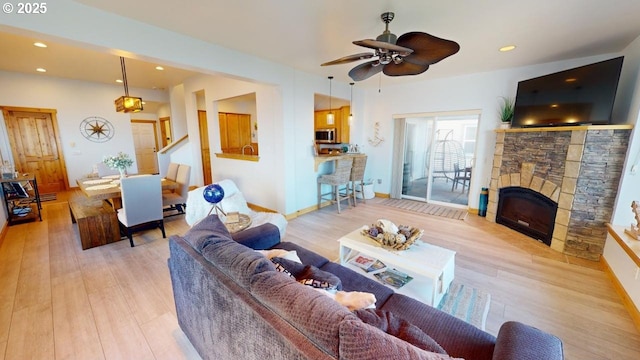 living room featuring a fireplace, light hardwood / wood-style flooring, and ceiling fan