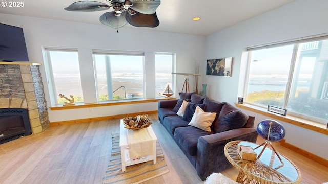 living room featuring heating unit, ceiling fan, a fireplace, and light wood-type flooring