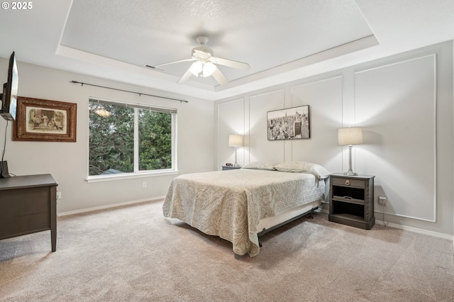 bedroom featuring carpet floors, a textured ceiling, ceiling fan, and a tray ceiling