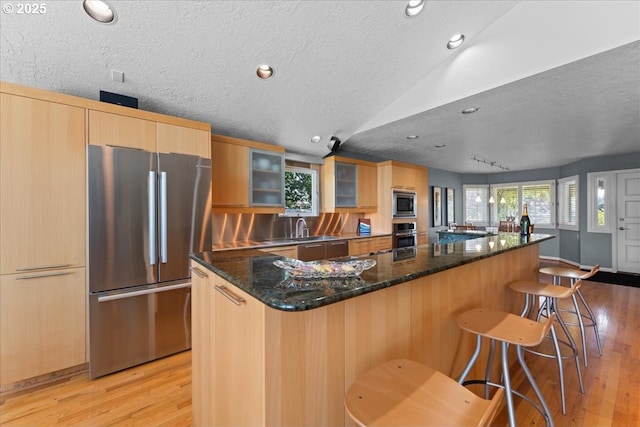 21047 NE Interlachen Ln, Fairview, OR 97024 - kitchen with stainless steel appliances, a textured ceiling, light wood-style flooring, a kitchen bar, and vaulted ceiling
