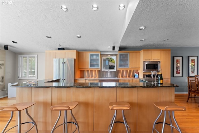 21047 NE Interlachen Ln, Fairview, OR 97024 - kitchen featuring stainless steel appliances, a textured ceiling, light wood-style flooring, light brown cabinets, and glass insert cabinets