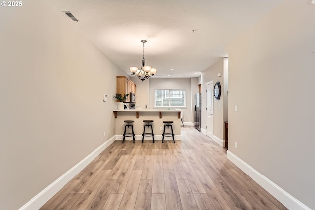 18445 SW Stepping Stone Dr Unit 16, Beaverton, OR 97003 - kitchen with a breakfast bar area, light wood-style floors, a chandelier, stainless steel fridge, and a peninsula