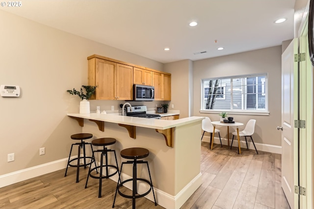 18445 SW Stepping Stone Dr Unit 16, Beaverton, OR 97003 - kitchen featuring stainless steel appliances, a peninsula, light brown cabinets, light countertops, and a breakfast bar