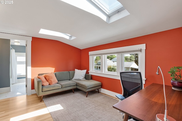 living area featuring wood finished floors and vaulted ceiling with skylight