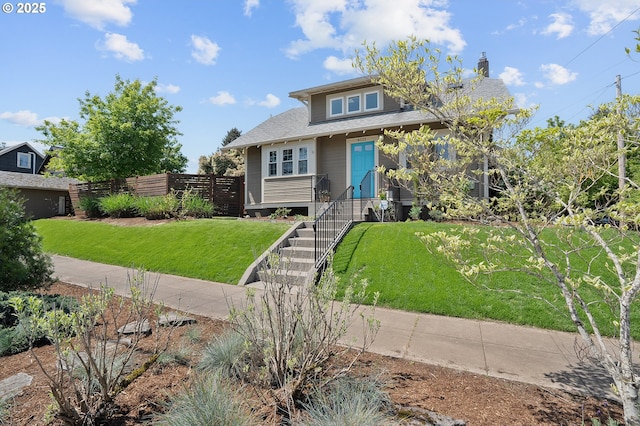 view of front facade with a shingled roof, a front lawn, and fence