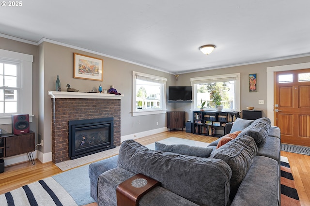 living room with baseboards, ornamental molding, a fireplace, and wood finished floors