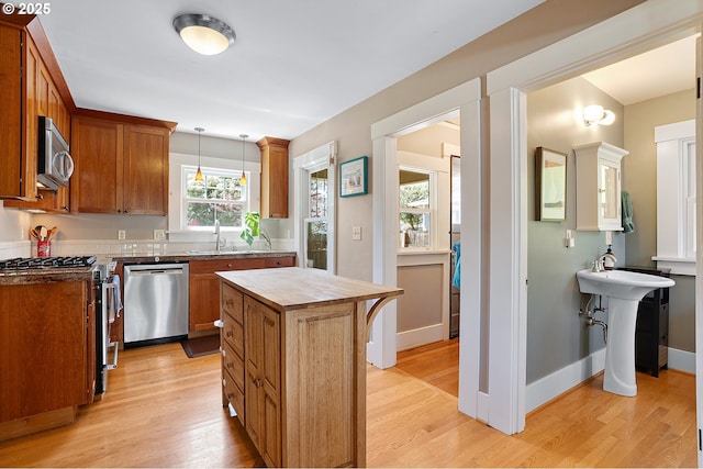 kitchen featuring light wood-style floors, pendant lighting, appliances with stainless steel finishes, and a kitchen island