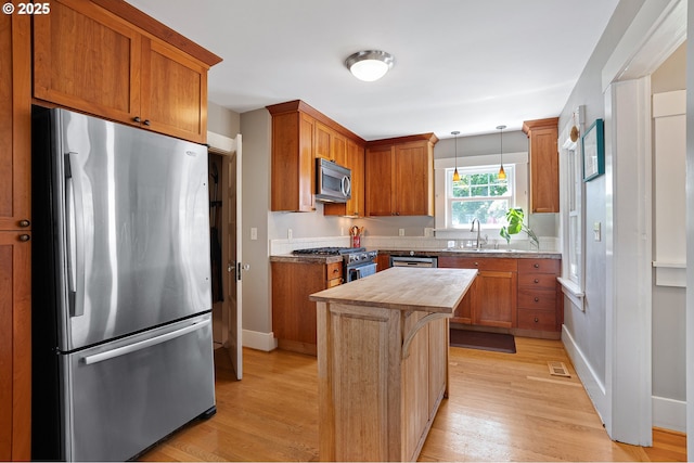 kitchen featuring a sink, appliances with stainless steel finishes, light wood-type flooring, and wood counters