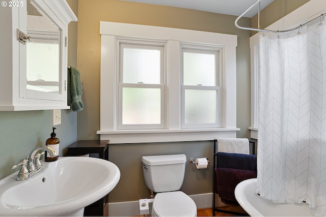 bathroom featuring toilet, curtained shower, and a sink