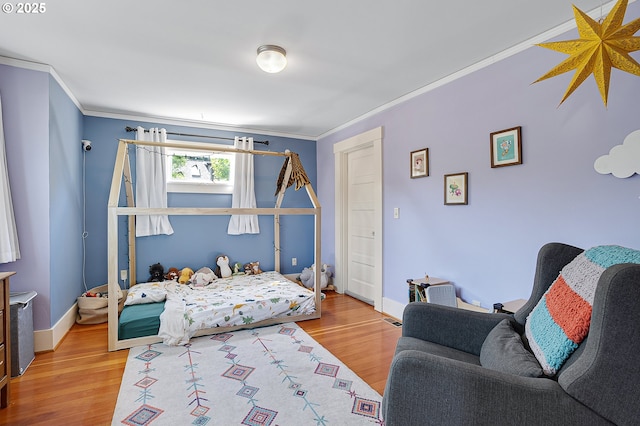 bedroom with crown molding, baseboards, and wood finished floors