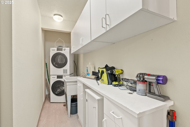 2211 SW Park Pl, Portland, OR 97205 - washroom with stacked washer / drying machine, light wood finished floors, and cabinet space