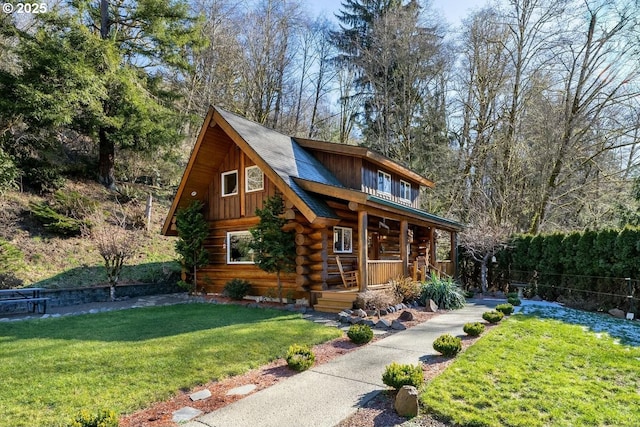 log cabin with covered porch and a front lawn